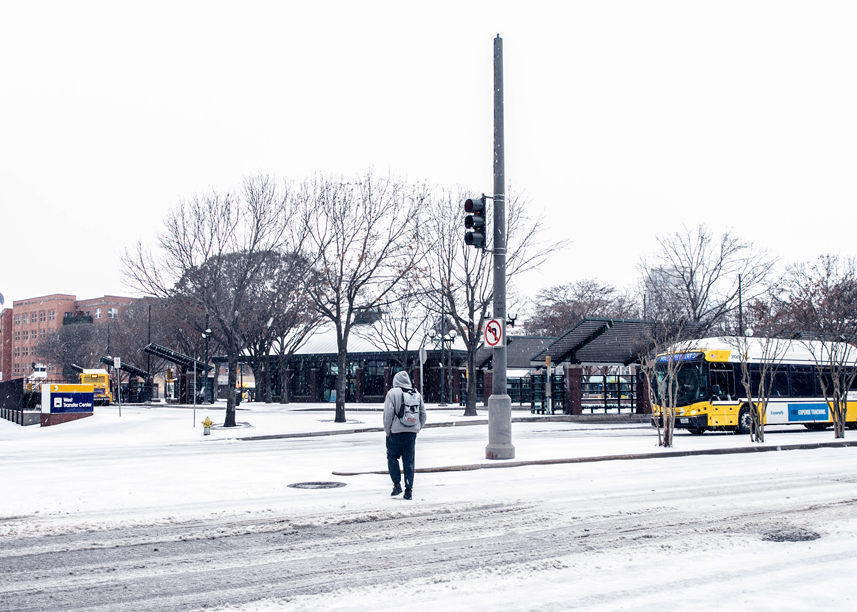 Man walking across snow covered Dallas street to get to DART station