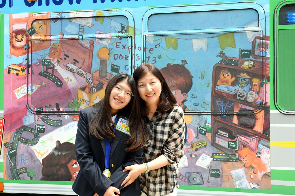 Girl and her mother standing in front of DART wrapped bus